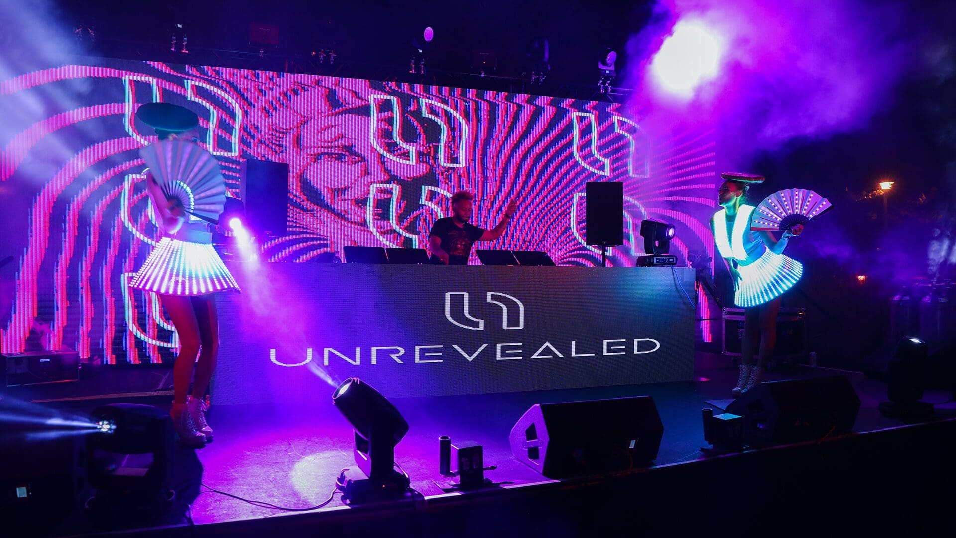 "DJ performance with illuminated dancers and visuals."